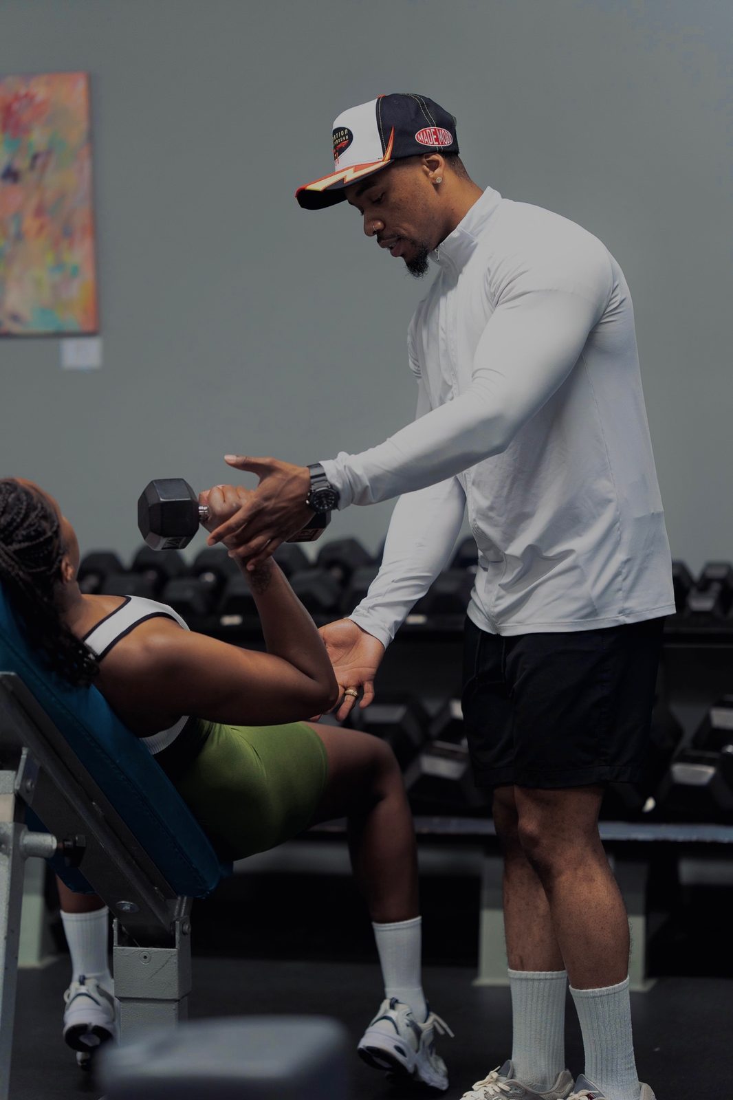 Bobby J correcting a client's arm position during a dumbbell curl
